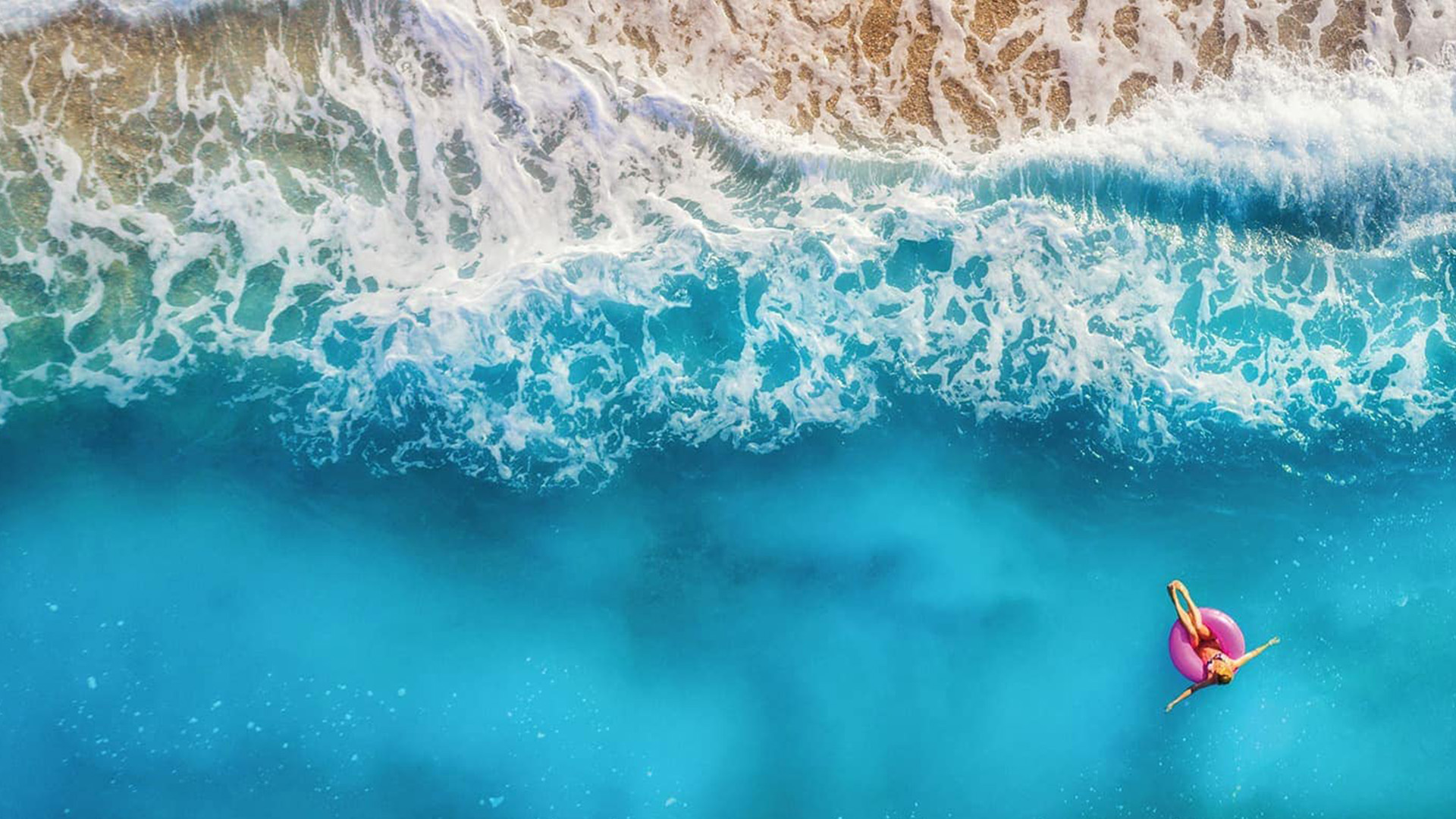 A photo of a girl relaxing in the ocean just off of the shore